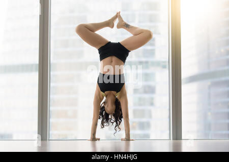 Young attractive woman in dance pose near floor window, handstan Stock Photo