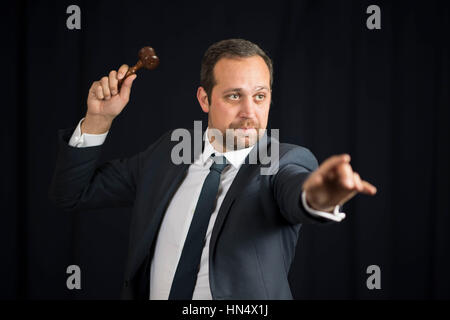 A male auctioneer in action holing a gavel during a live auction. Stock Photo