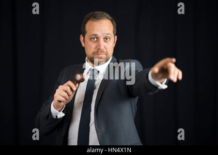 A male auctioneer in action holing a gavel during a live auction. Stock Photo