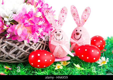 Easter decoration with bunnies, eggs and flowers in basket on artificial grass. Stock Photo