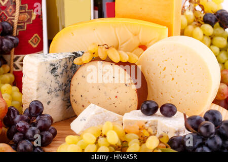 Various type of cheese, wines and grapes on wooden board closeup picture. Stock Photo