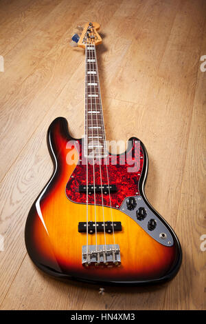 Bath, United Kingdom - November 7, 2011: A Fender re-issue 1970s Jazz Bass laid on a wooden floor. The bass guitar, made in Mexico, replicates the vin Stock Photo