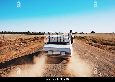 3 guys on a road trip along a Rural dirt road in the desert. Stock Photo