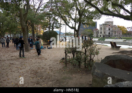 View of Atomic Bomb Dome in Hiroshima, Japan, Asia with young Japanese students, school children playing and having fun in park Stock Photo