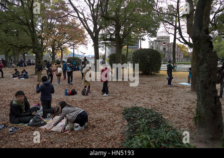 View of Atomic Bomb Dome in Hiroshima, Japan, Asia with young Japanese students, school children playing and having fun in park Stock Photo