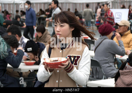 Japanese people, families, tourists eating traditional Asian street food at city fair. Hiroshima, Japan, Asia Stock Photo