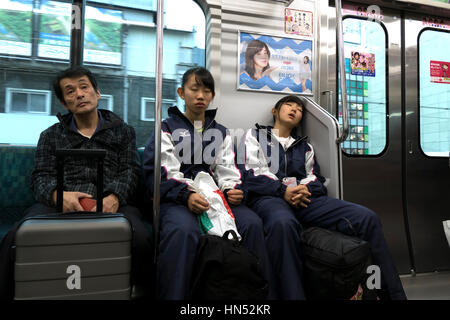 Asian people, Japanese girls, commuters napping while traveling on a local train in Tokyo, Japan, Asia. Railway, transportation Stock Photo