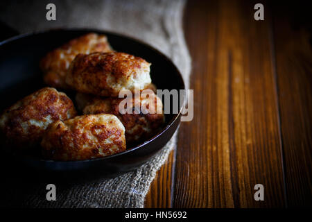 fried pork chops in a frying pan on a wooden table Stock Photo