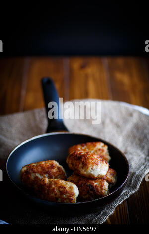 fried pork chops in a frying pan on a wooden table Stock Photo