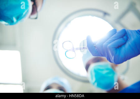 Assistant passing surgical scissors to the doctor Stock Photo