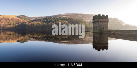 Stone towers of Derwent dam reflected in still water on a winter morning, Peak District national park, Derbyshire, England Stock Photo