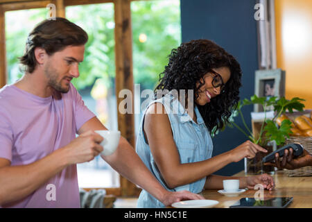 Woman entering pin code on credit card reader at counter in cafÃƒÂ© Stock Photo