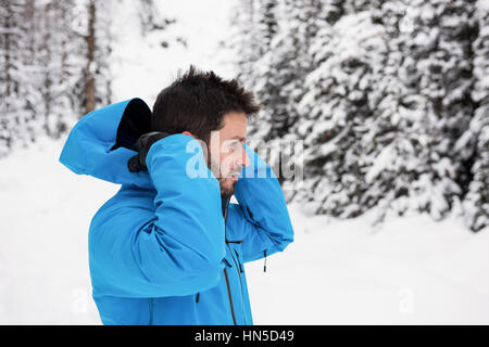 Side view of skier wearing hooded jacket on snowy mountains Stock Photo
