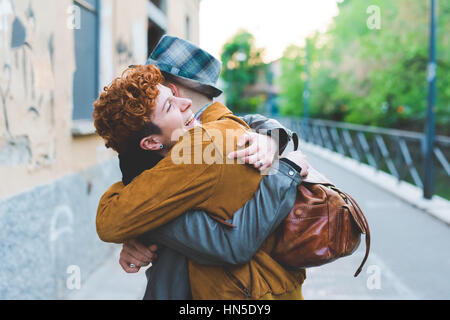 Two friends man and woman meeting in the street of the city, smiling and hugging –friendship, happiness concept Stock Photo