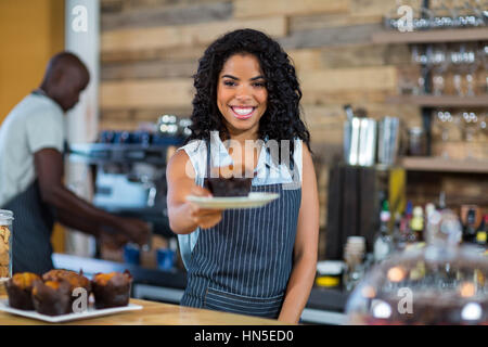 Waiter serving a cup cake at counter in cafe Stock Photo