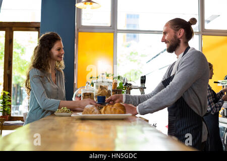 Waiter serving a cup of coffee to customer at counter in cafÃƒÂ© Stock Photo