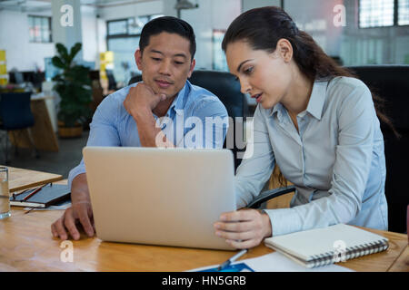 Business executives discussing over laptop in office Stock Photo