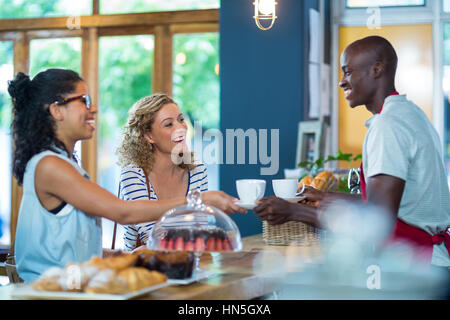 Waiter serving coffee to female customers in cafÃƒÂ© Stock Photo
