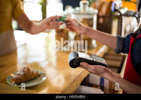 Mid-section of customer making payment through credit card at counter in cafÃƒÂ© Stock Photo