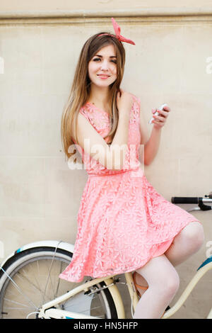 girl sitting on bicycle with mobile phone. Stock Photo