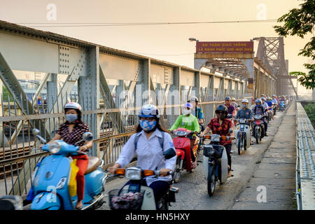 Heavy commuter traffic on the pedestrian walkway of the Long Bien cantilever bridge, with riders using face masks, Hanoi, Vietnam Stock Photo