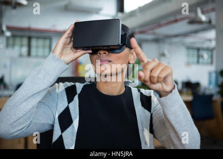 Businesswoman using virtual reality headset in office Stock Photo