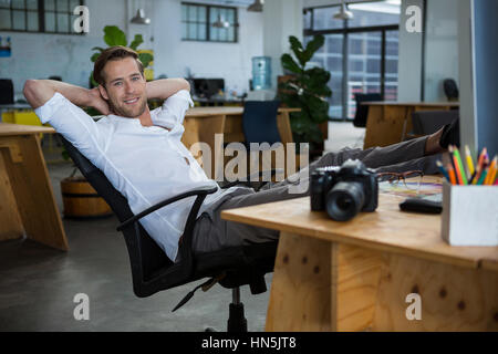Smiling male graphic designer relaxing on the chair in office Stock Photo