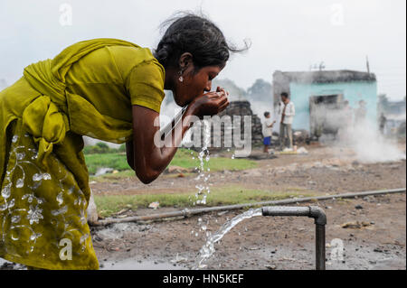 INDIA, state Jharkhand, Jharia Dhanbad , parts of Jharia are located above smolding underground coal seams and will be displaced due to extended opencast coal mining by BCCL Ltd. of Coal India, people fetch and drink water from well Stock Photo