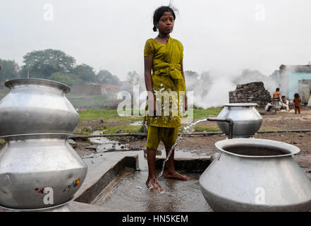 INDIA, state Jharkhand, Jharia Dhanbad , parts of Jharia are located above smolding underground coal seams and will be displaced due to extended opencast coal mining by BCCL Ltd. of Coal India, people fetch water from well Stock Photo