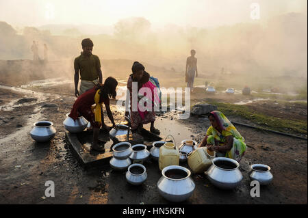 INDIA, state Jharkhand, Jharia Dhanbad , parts of Jharia are located above smolding underground coal seams and will be displaced due to extended opencast coal mining by BCCL Ltd. of Coal India, people fetch water in the morning Stock Photo