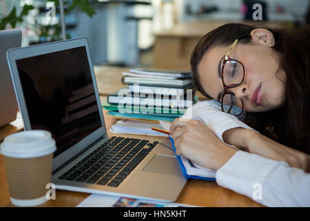 Tired female graphic designer sleeping at desk in office Stock Photo