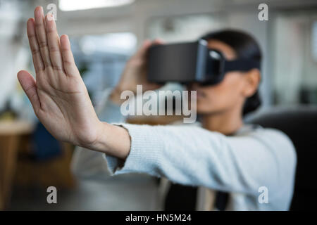 Businesswoman using virtual reality headset in office Stock Photo