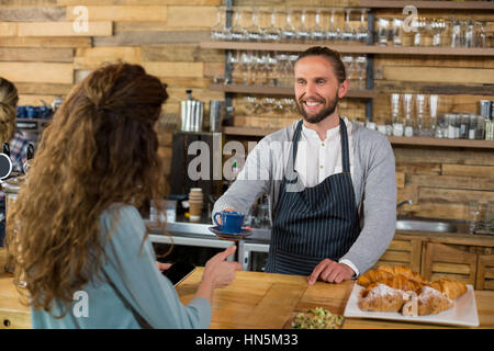 Waiter serving a cup of coffee to customer at counter in cafÃƒÂ© Stock Photo