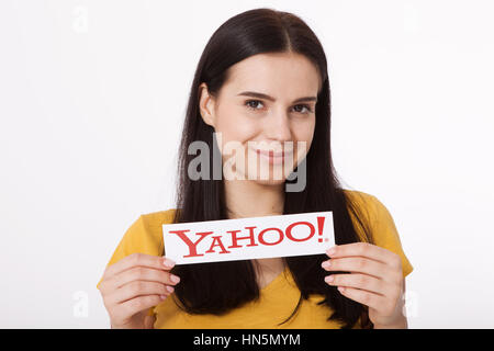 Kiev, Ukraine - August 22, 2016: Woman hands holding the logo of the brand Yahoo icons printed on paper on grey background. Stock Photo