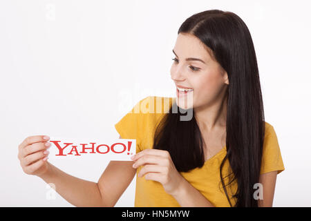 Kiev, Ukraine - August 22, 2016: Woman hands holding the logo of the brand Yahoo icons printed on paper on grey background. Stock Photo