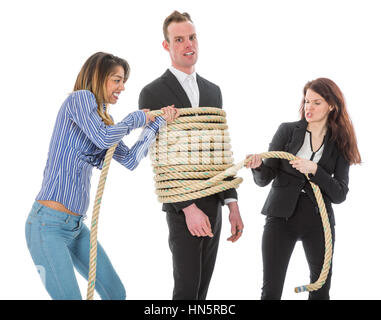 Two angry woman tying a business man with rope, isolated on a white background Stock Photo