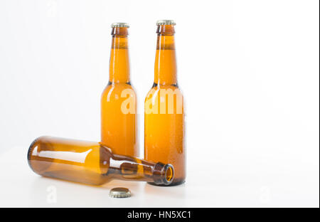 Empty and full brown beer bottles set against a white background Stock Photo