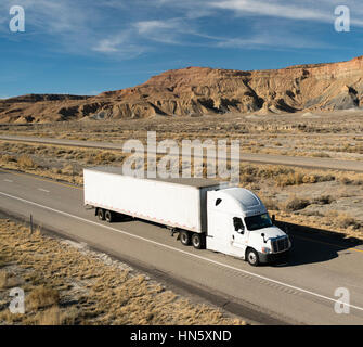 A white big rig rolls across Utah on a divided highway Stock Photo