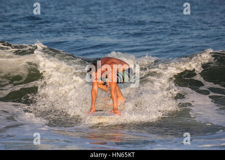 A young man in his early 20's surfing. He has caught a wave in the Atlantic Ocean. The location is the New Jersey Shore. Stock Photo