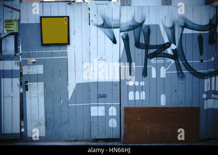 A shaky construction site door with a wooden fence forms a construction site barrier. Stock Photo