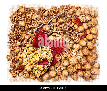 Walnut kernels in heart shaped box, whole walnuts, nutshells and nutcracker background as healthy eating and dieting concept, top view, flat lay Stock Photo