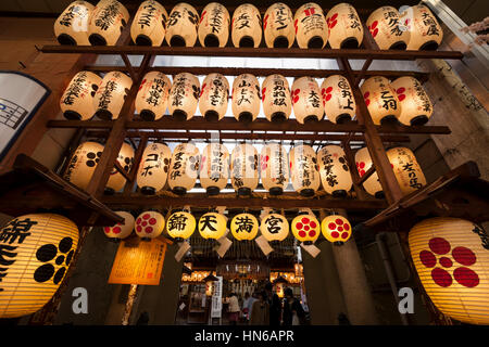 Kyoto, Japan - March 20, 2012: Illuminated paper lanterns hanging above the entrance of Nishiki Tenmangu Shrine on Teramachi shopping street in downto Stock Photo