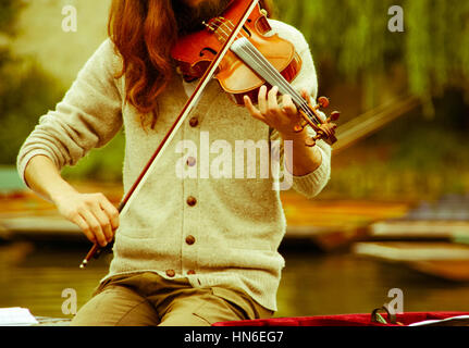 Man playing the violin by the river Stock Photo