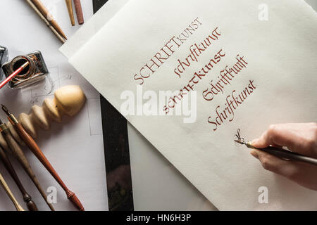 Calligraphy studio, hand writes text with ink pen and nib, Anglaise writing on Ingres paper, inkwell and pen holder at back Stock Photo