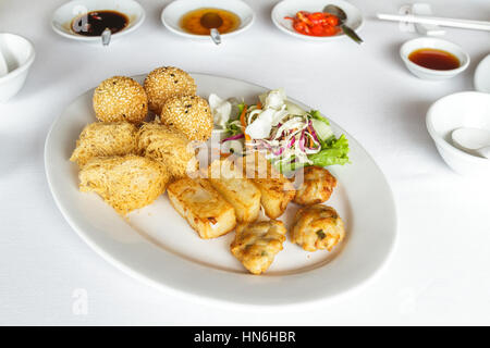 Dim sum mix have Deep fried stuffing mashed soybean, Deep fried taro, Deep fried squid and Fried turnip cake in white plate at restaurant with soy sau Stock Photo