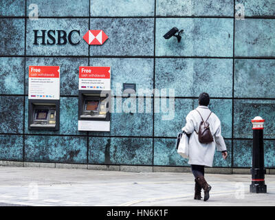 HSBC Cash Machines London - A woman walks towards HSBC cash machines in Central London with security cameras monitoring the ATMs. Stock Photo
