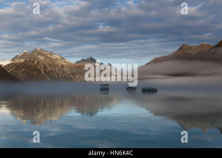 Three boats on a calm morning on Crescent Lake near Mount Redoubt, Lake Clark National Park, Alaska, USA Stock Photo
