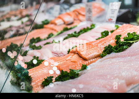 Seafood stand with cuts and filets of salmon and tuna on ice behind glass Stock Photo