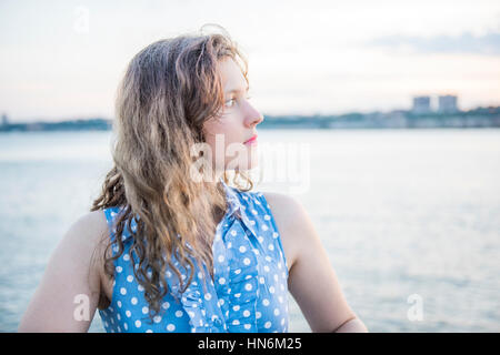 Profile of young woman in blue polka dot dress looking at Hudson River in New York City Stock Photo
