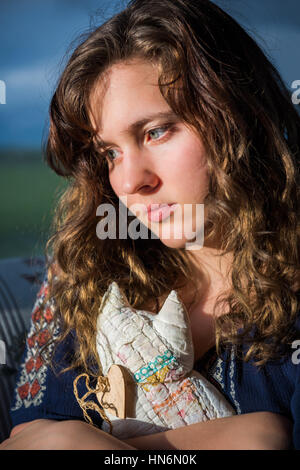 Portrait of lonely young woman looking sad holding stuffed cat toy Stock Photo